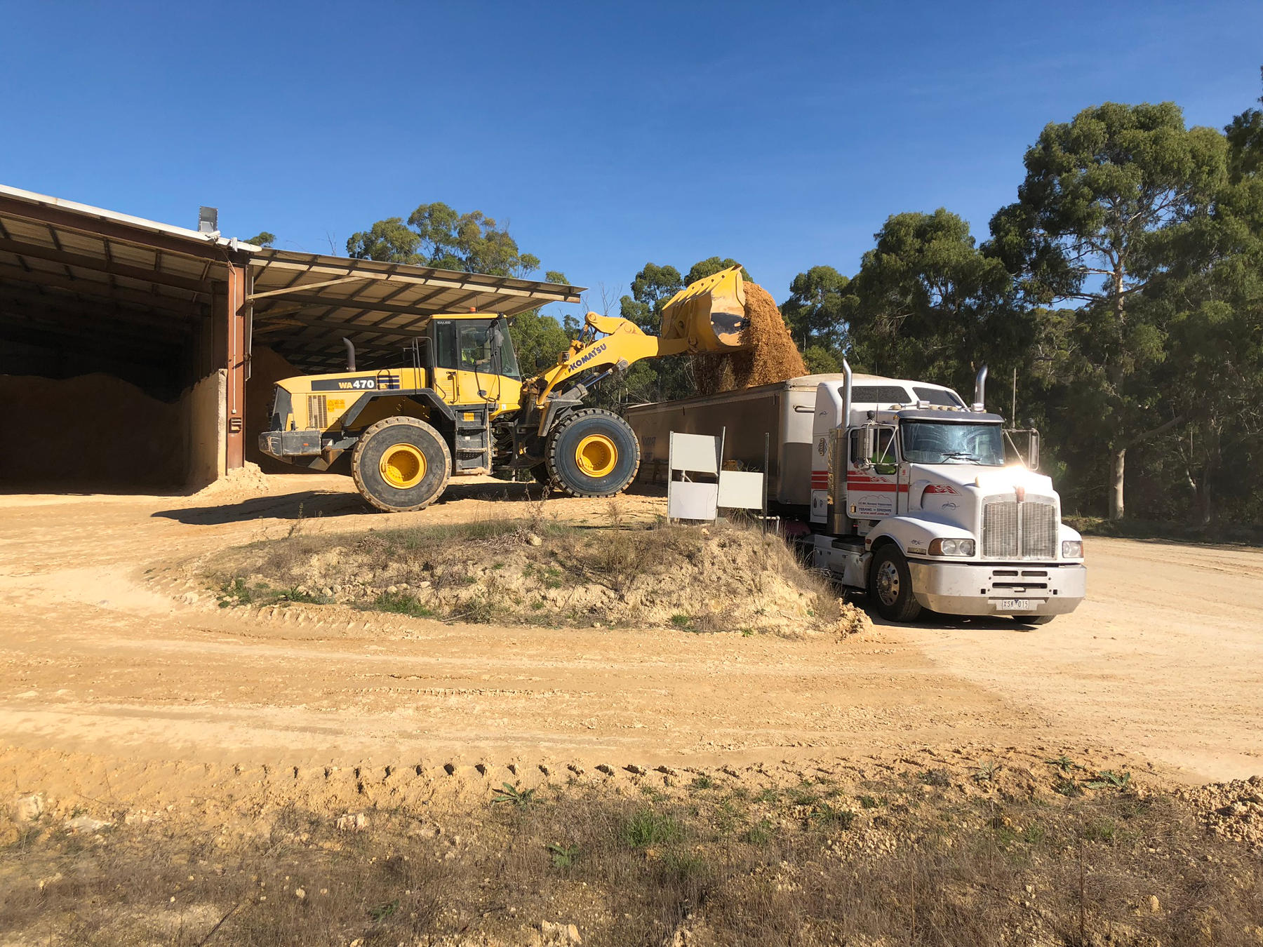 Frontloader depositing limestone fertiliser into delivery truck